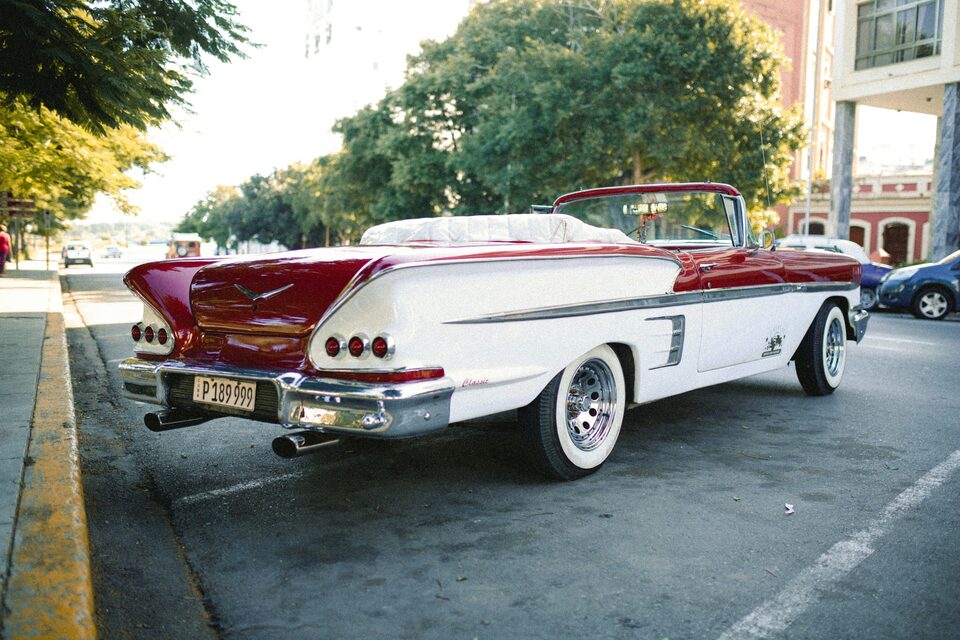 A red and white classic Chevrolet Impala convertible on a sunny street