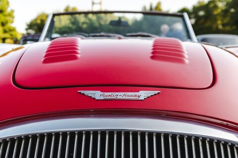The red hood and chrome grille of a classic roadster