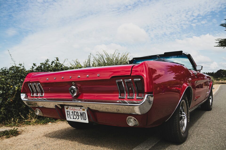 A red classic Ford Mustang convertible in the sun