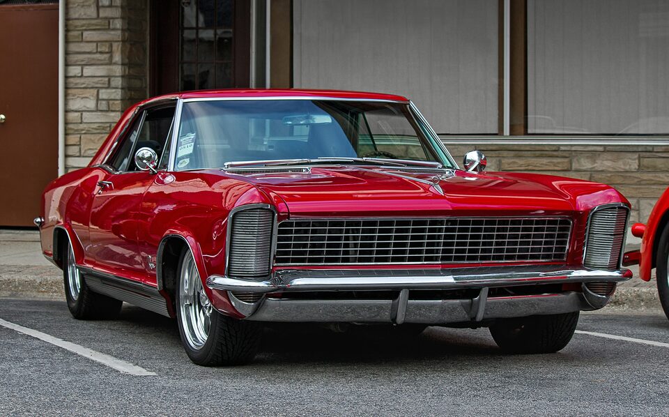 A red classic Buick Riviera parked on a city street