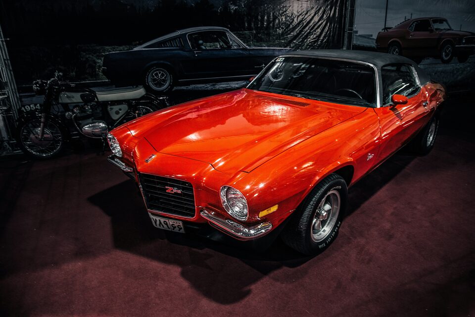 An orange classic Chevrolet Camaro in a showroom