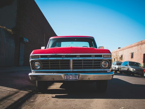 A red classic Ford pickup under a blue sky