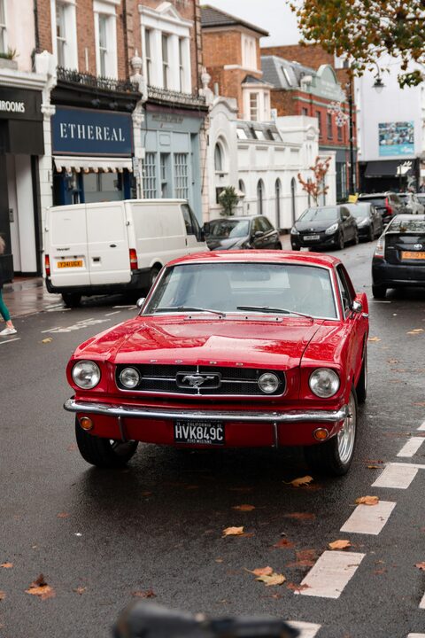 A red classic Ford Mustang on a city street