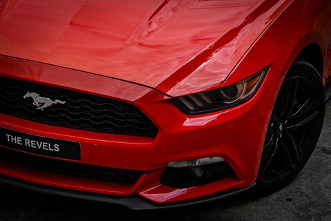 The hood and running horse badge of a red Ford Mustang