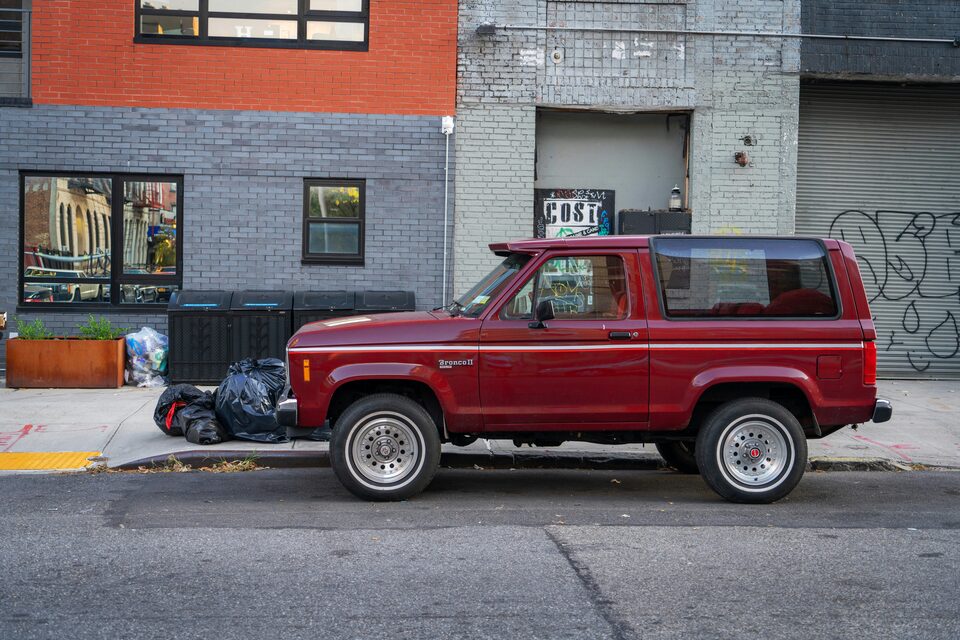 A red Ford Bronco parked on a city street