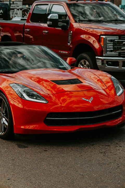 A red Corvette and a red pickup on a dealer lot