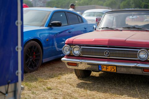 A blue sports car beside a red classic sedan at a show