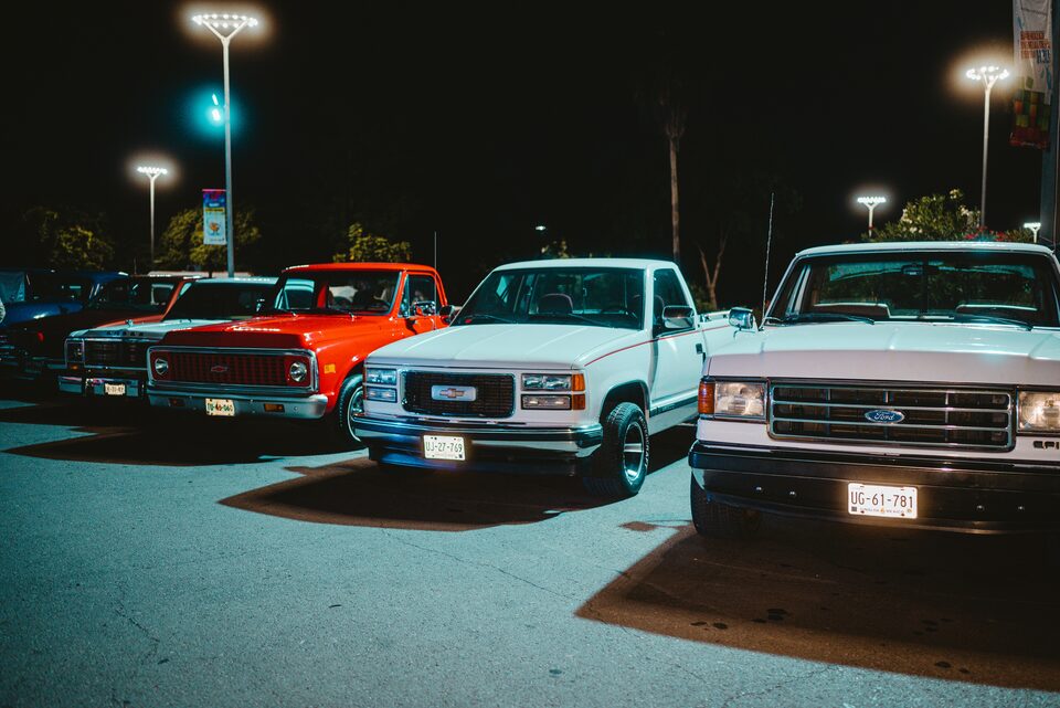 Classic pickups parked under lights at night