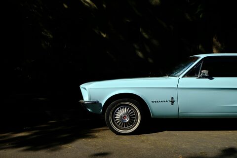 A light blue Ford Mustang in dramatic light
