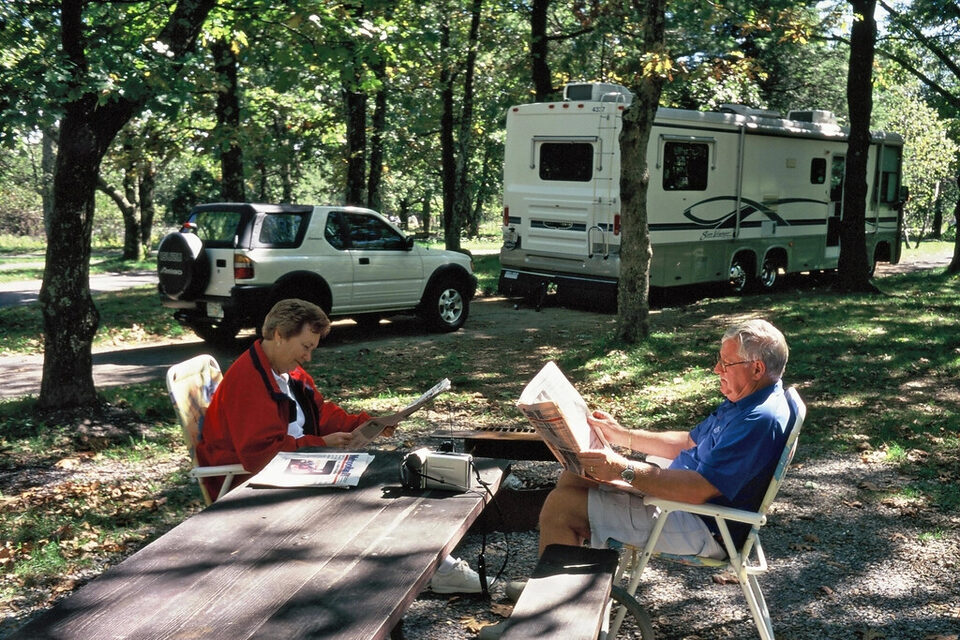 Two campers relaxing beside their RV