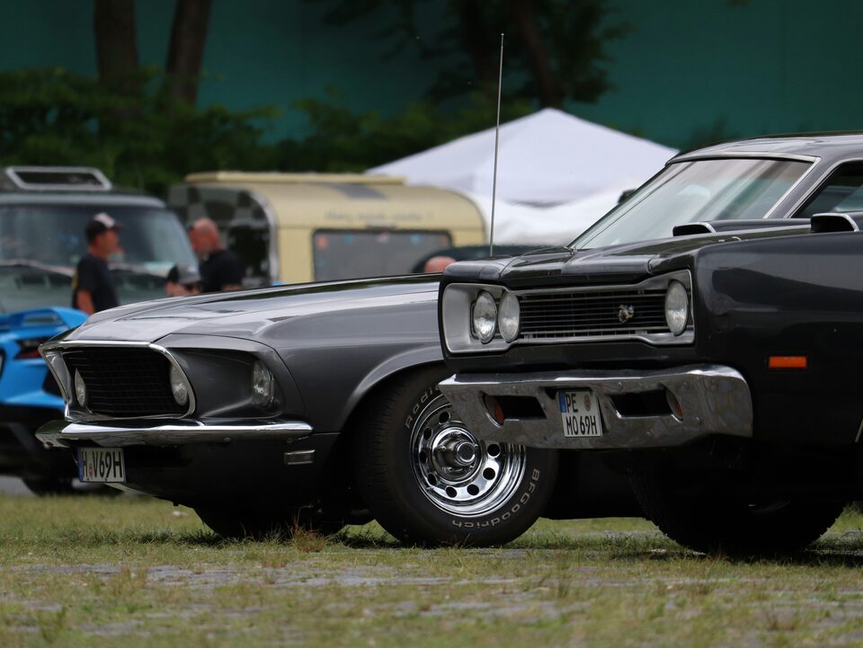 A dark classic Ford Mustang at an outdoor car show