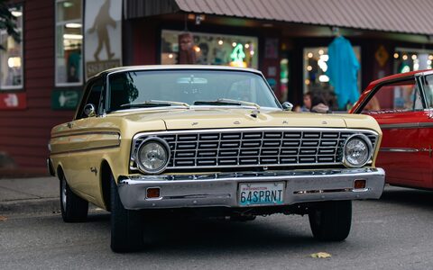 A cream classic Ford Falcon parked on a city street