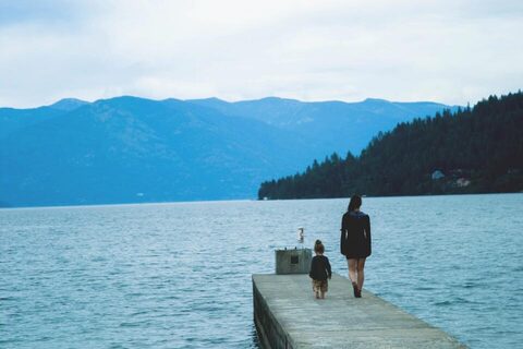 Two people on a dock by a mountain lake