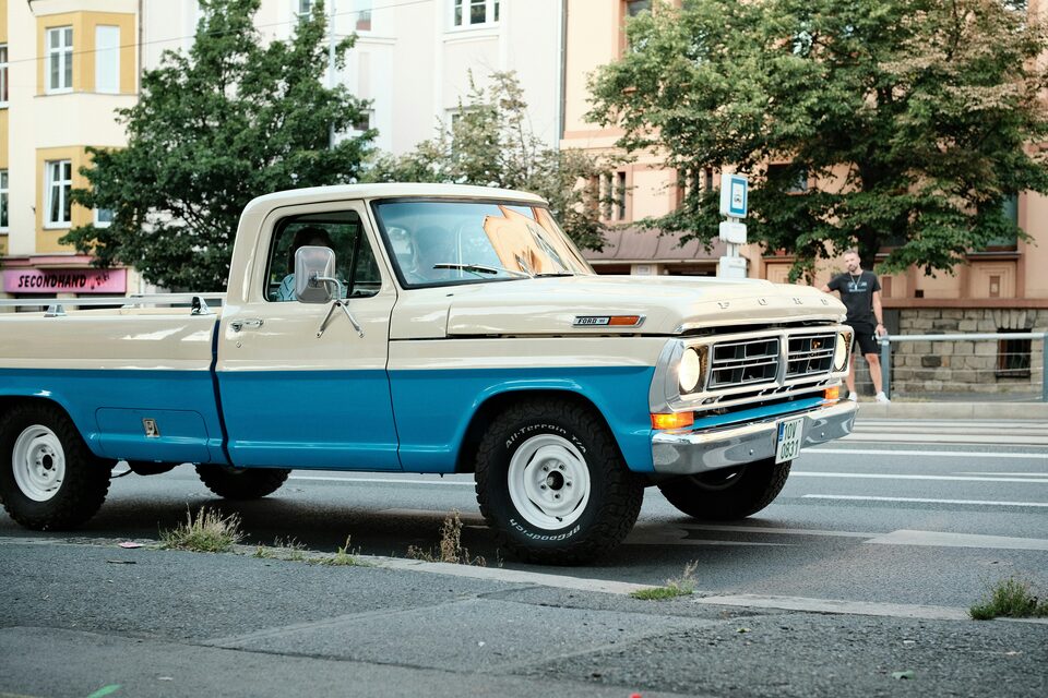 A restored two-tone Ford pickup parked on a city street