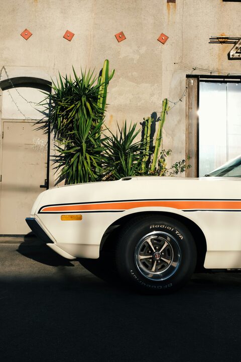 A white classic car with an orange racing stripe