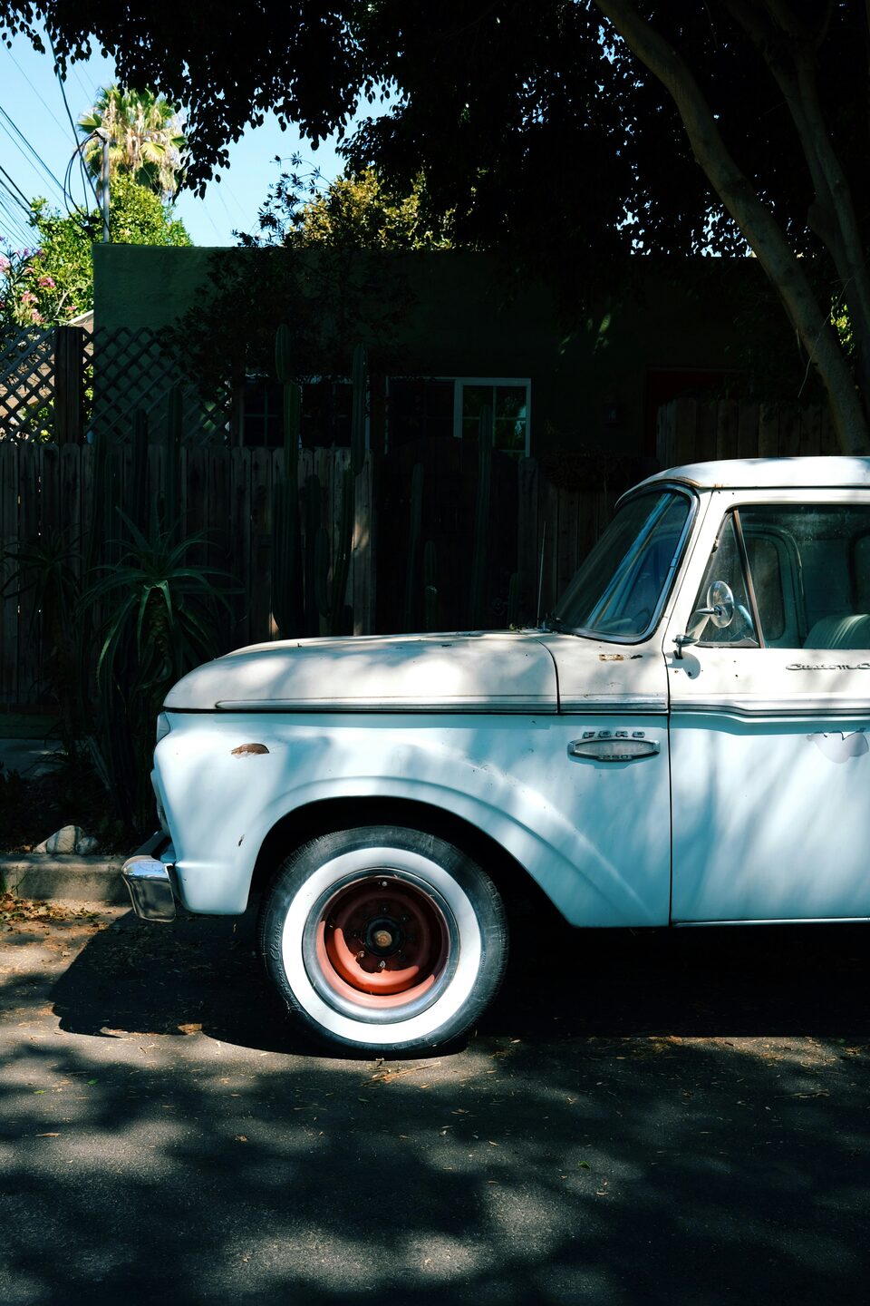 A white classic pickup truck in dappled shade