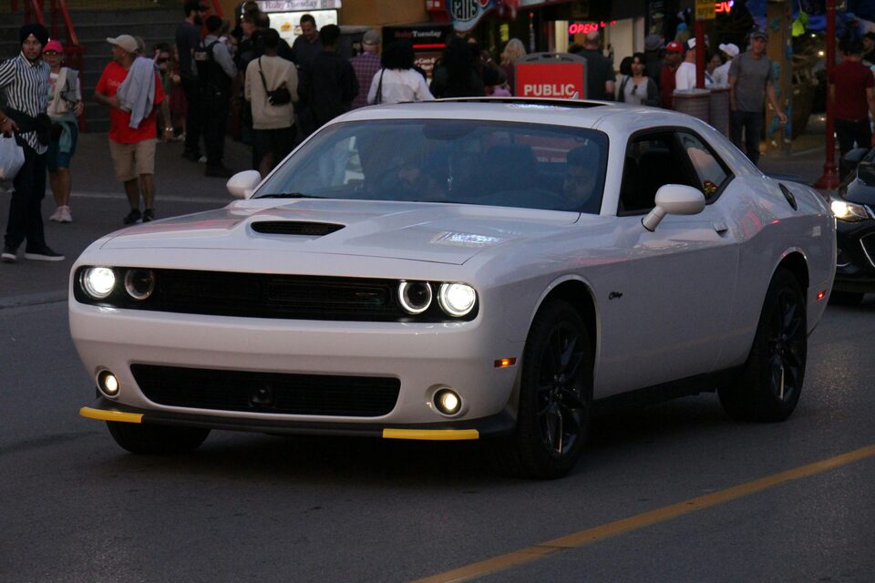 A white Dodge Challenger at an evening car meet