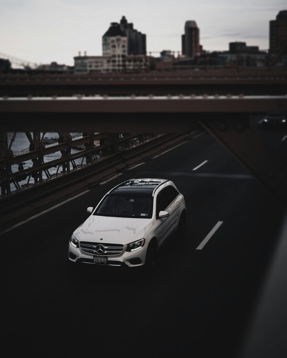 A white SUV driving on an open highway, seen from above