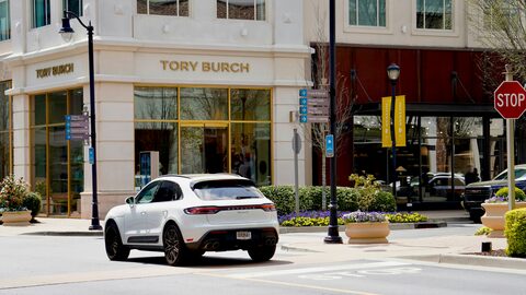 A white Porsche SUV outside an upscale storefront