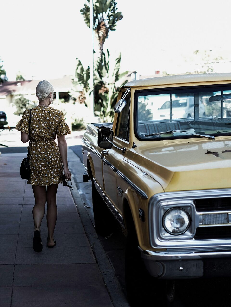 A woman walking beside a parked car