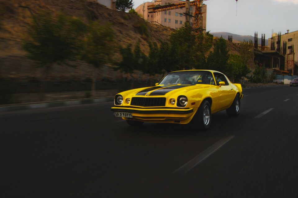 A yellow Chevrolet Camaro driving on an open road